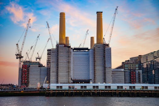 Battersea Power Station during redevelopment with cranes against a vibrant sunset sky in London, England.